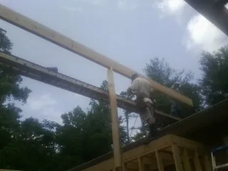 Carpenter setting a ridge beam over a new addition frame — Ice Dam Removal by Roofing Brothers in Kingwood