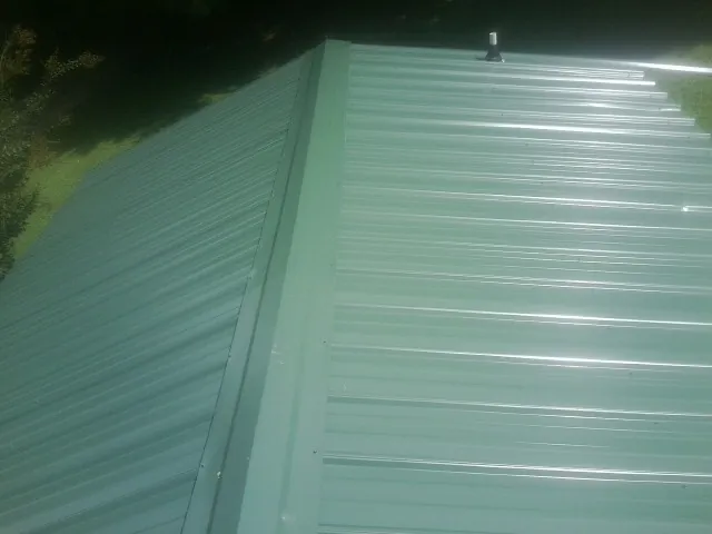 New green metal panels meeting at the ridge of a roof — Flat Roof Repair work by our crew in Kingwood