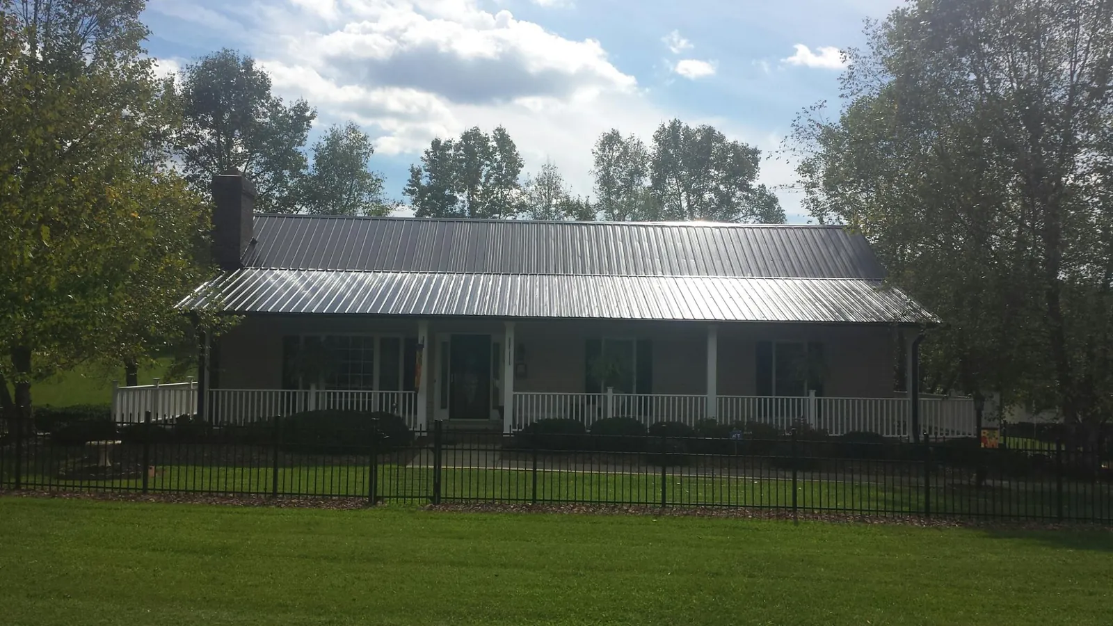 Gray metal roof on a brick ranch with a full width front porch — Gutter Guard Installation work by our crew in Kingwood