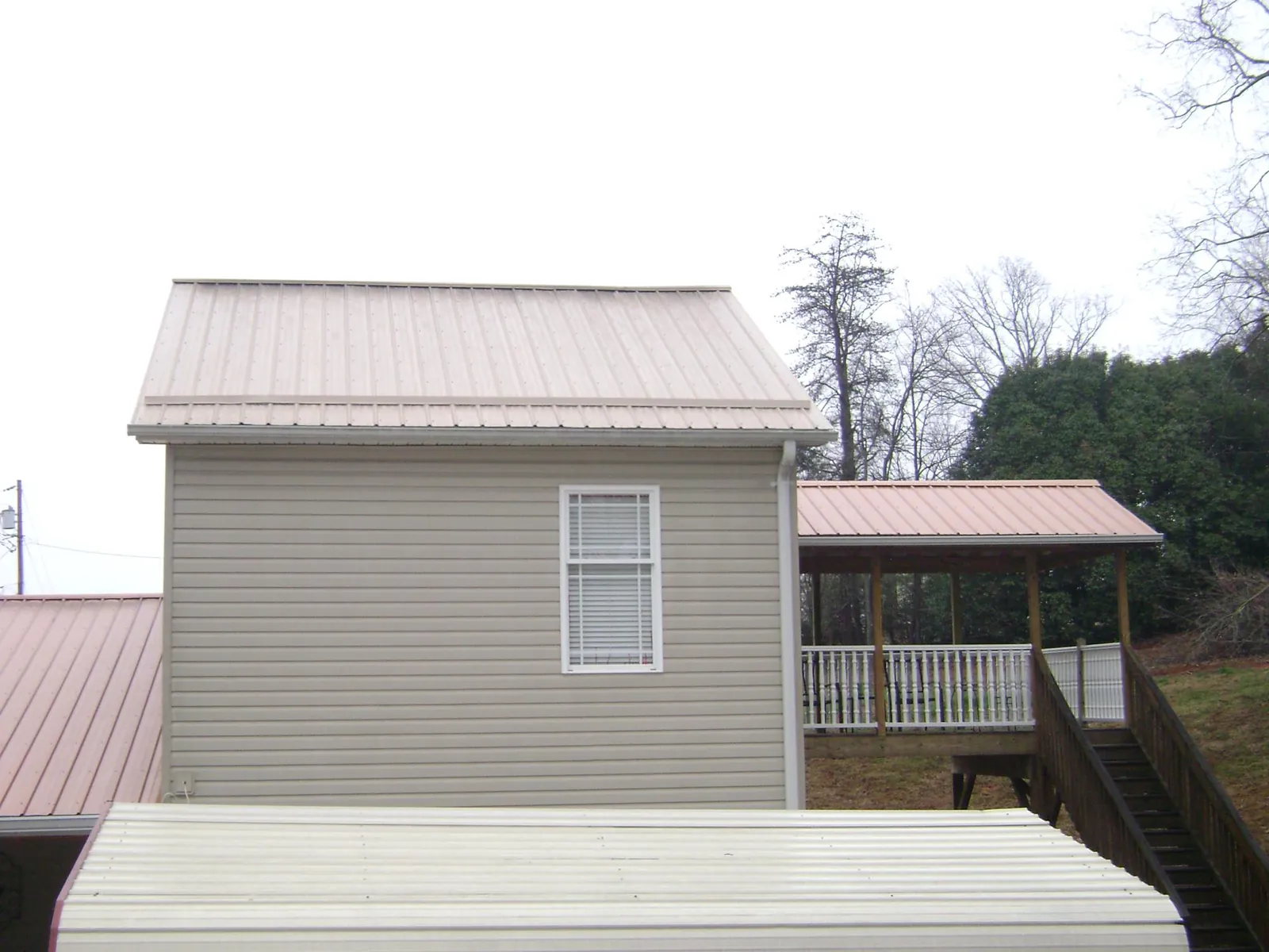 Tan metal roofs on a two story addition and attached porch, from a Roof Replacement job in Kingwood